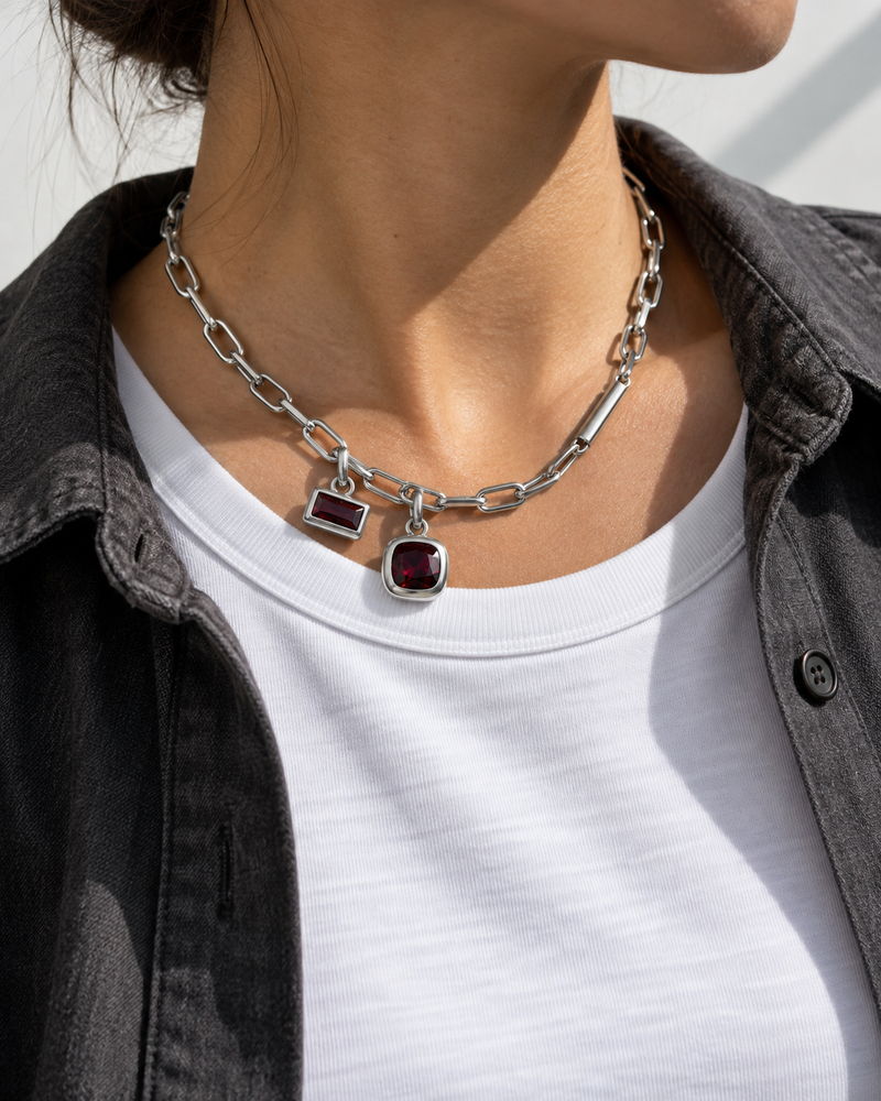 AI design reference: a model wearing an asymmetric chain with two garnet charms.