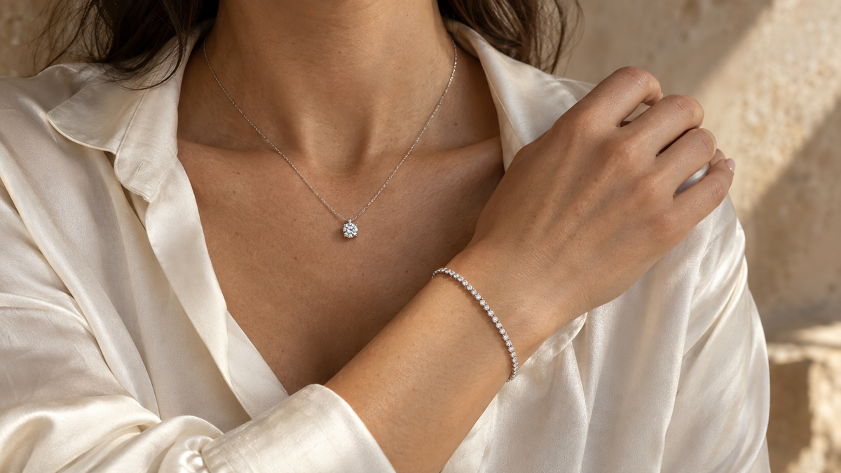 Diamond pendant and tennis bracelet worn with an ivory shirt; editorial design reference